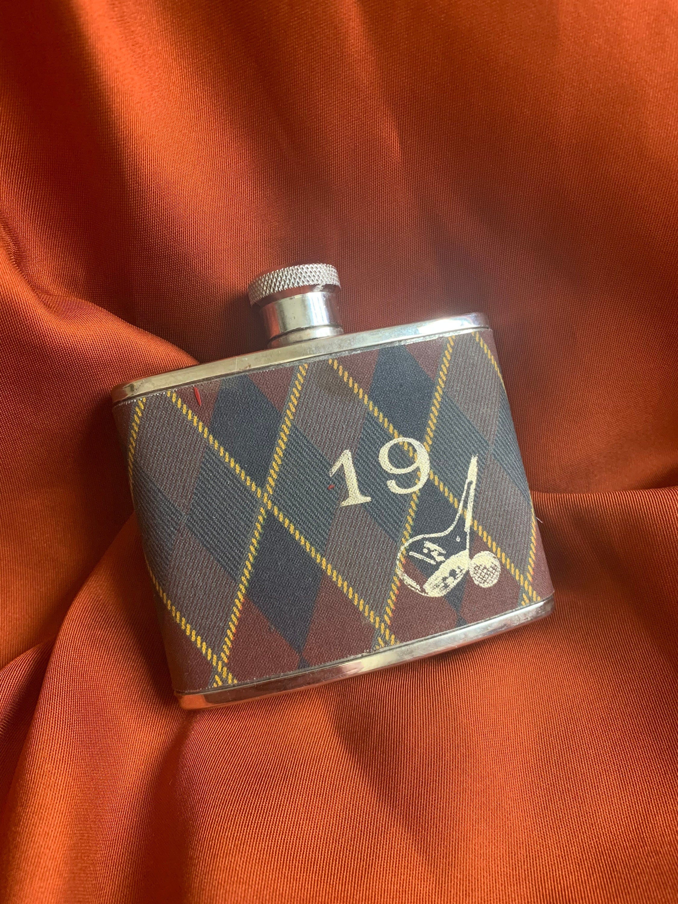 Stainless steel made in England flat curved vintage flask covered with plaid fabric with embroidered golf symbols and number 19.