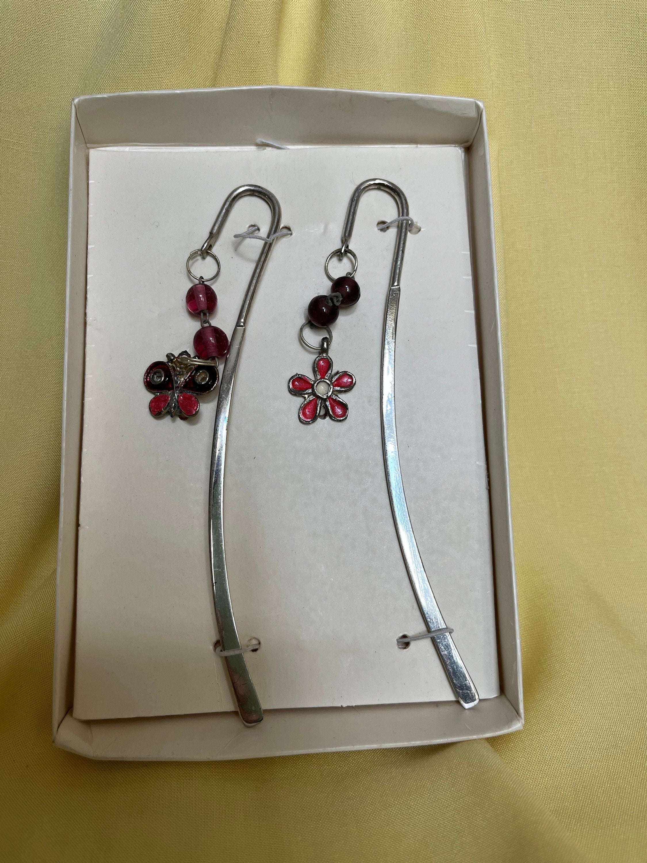 A pair of vintage made in India silver metal and pink glass bookmarks with charms of a butterfly and a daisy